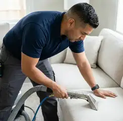 Professional upholstery cleaning technician using an extraction wand to deep-clean a fabric sofa, Mesa, AZ.