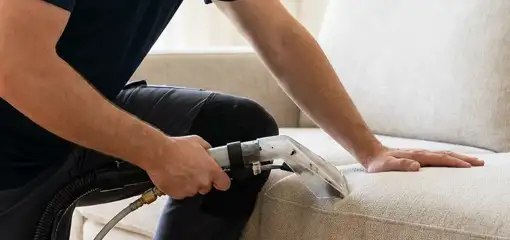 Professional upholstery cleaner deep-cleaning a fabric sofa with a handheld extraction tool, Mesa, AZ.